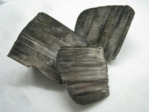 Lithium pellets covered in white lithium hydroxide (left) and ingots with a thin layer of black nitride tarnish (right)