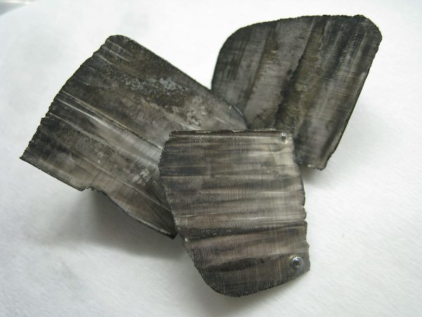 Lithium pellets covered in white lithium hydroxide (left) and ingots with a thin layer of black nitride tarnish (right)
