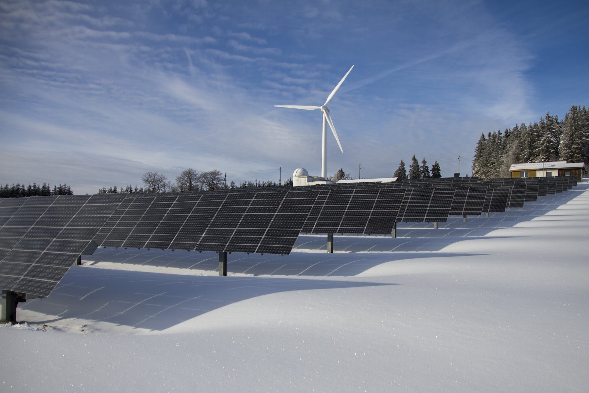 Trading Renewable Energy Certificates. solar panels on snow with windmill under clear day sky